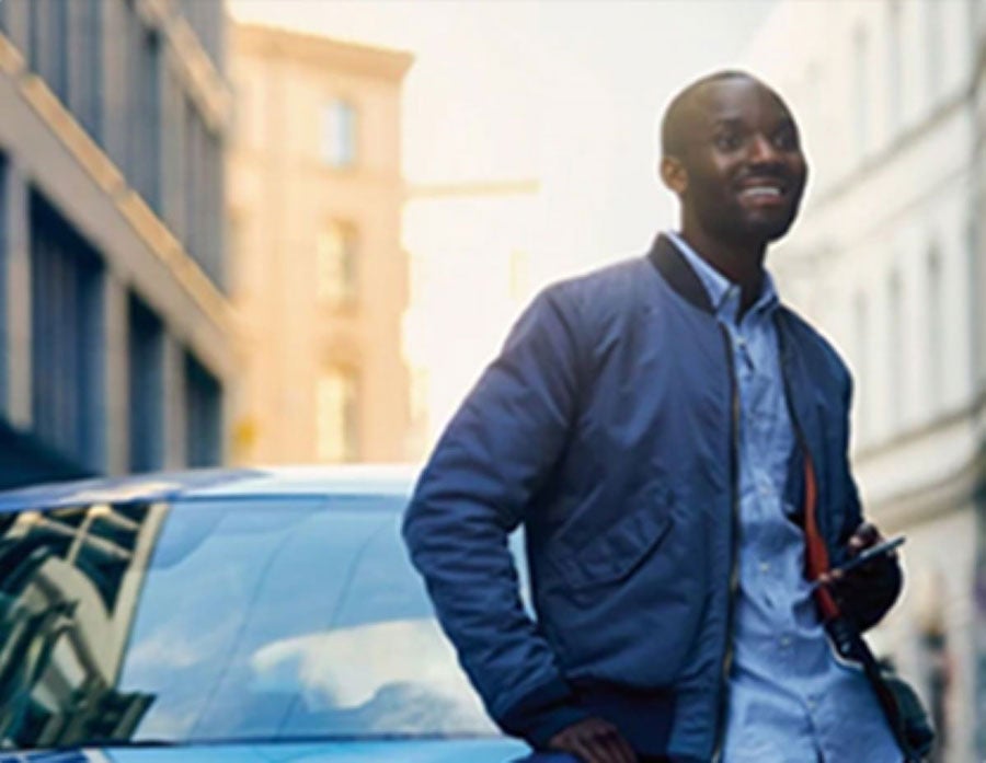 A man smiles in front of a parked BMW